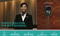 Temperature monitor with digital display on a wooden surface, next to a person in formal attire.